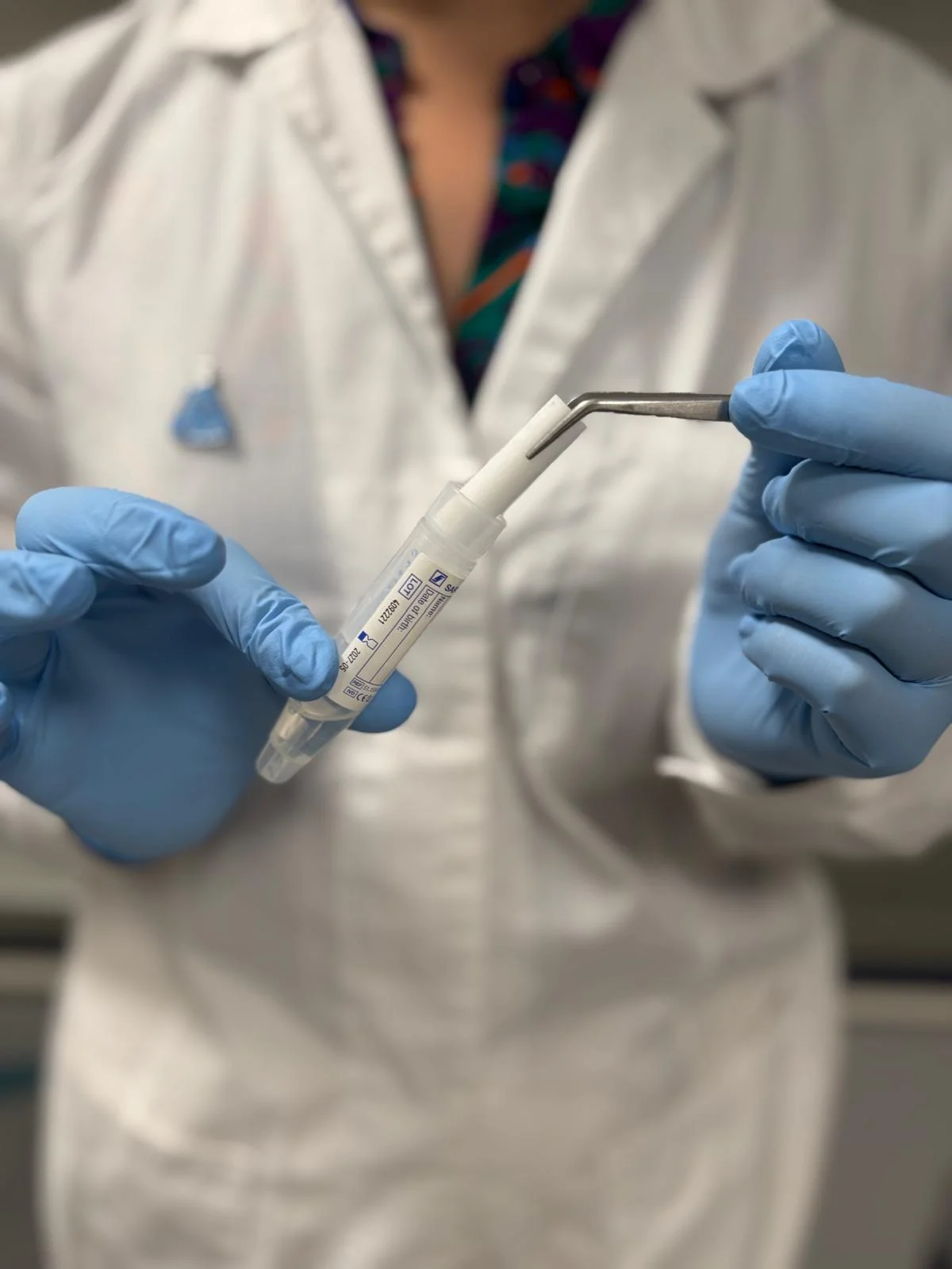 Gloved hands handling a saliva collection tube and swab